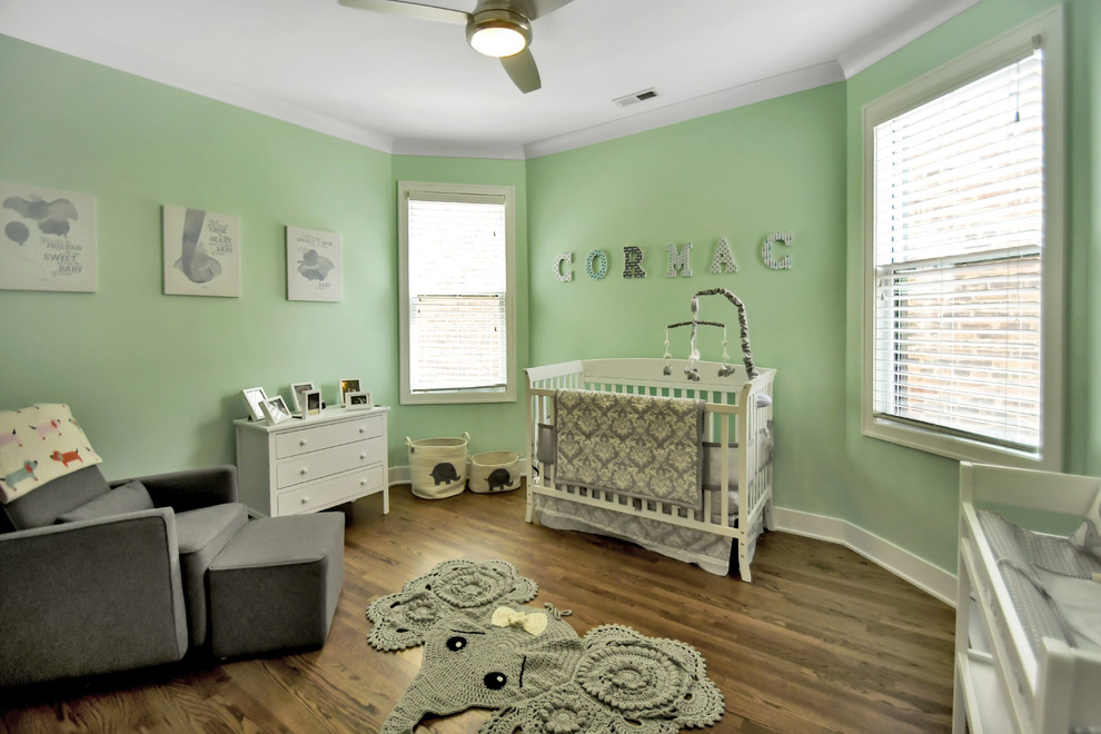 This is an example of a large transitional nursery for boys in Chicago with green walls, dark hardwood floors and brown floor.