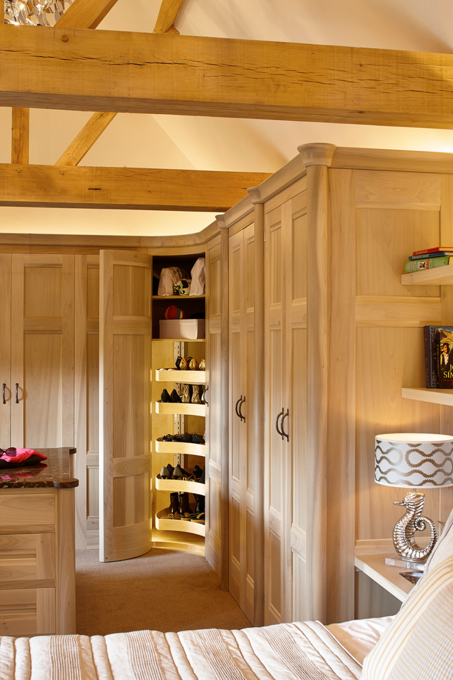 Inspiration for an expansive modern gender-neutral dressing room in Surrey with recessed-panel cabinets, light wood cabinets and carpet.