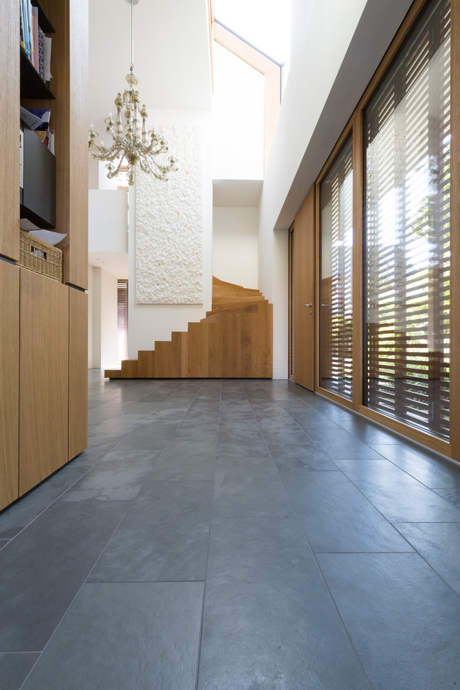 This is an example of a large modern hallway in Other with white walls, slate floors and grey floor.
