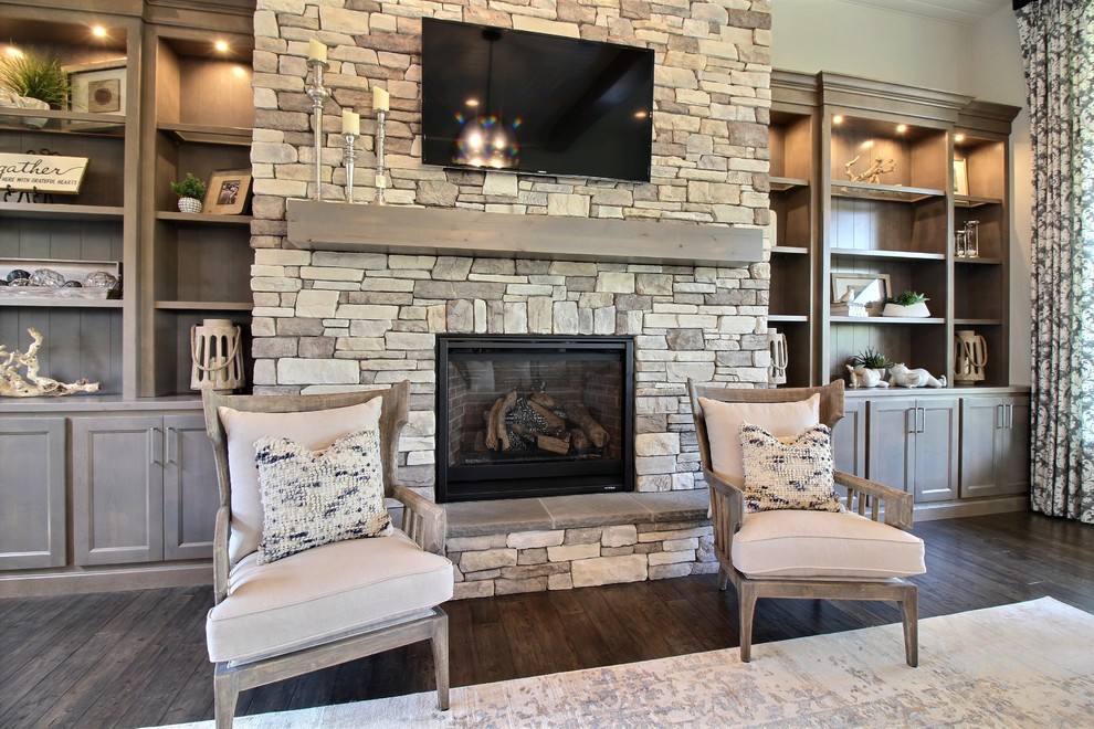 This is an example of an expansive arts and crafts open concept family room in Portland with beige walls, dark hardwood floors, a standard fireplace, a stone fireplace surround, brown floor and a wall-mounted tv.