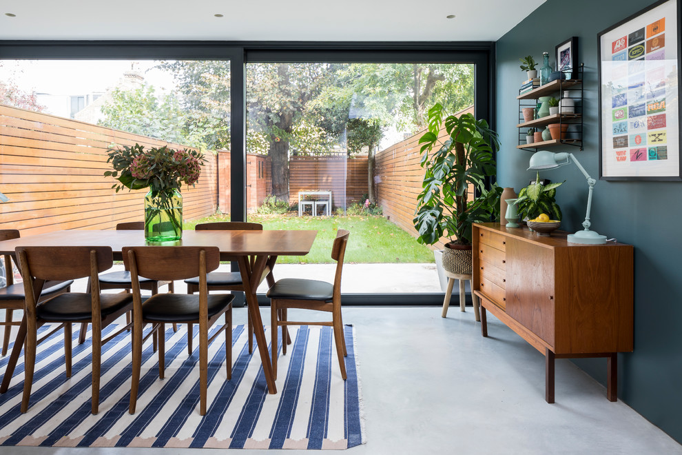 This is an example of a midcentury dining room in London with green walls and grey floor.