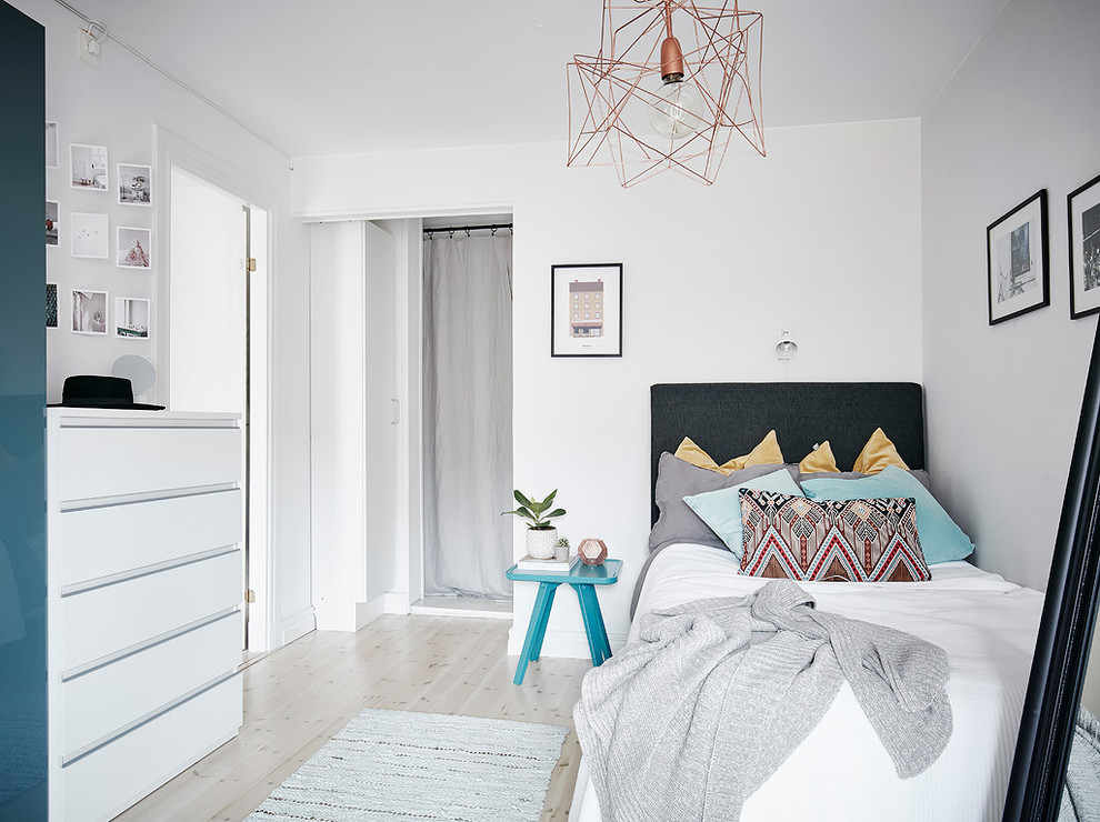 Minimalistisk inredning av ett mellanstort könsneutralt tonårsrum kombinerat med sovrum, med vita väggar, ljust trägolv och beiget golv