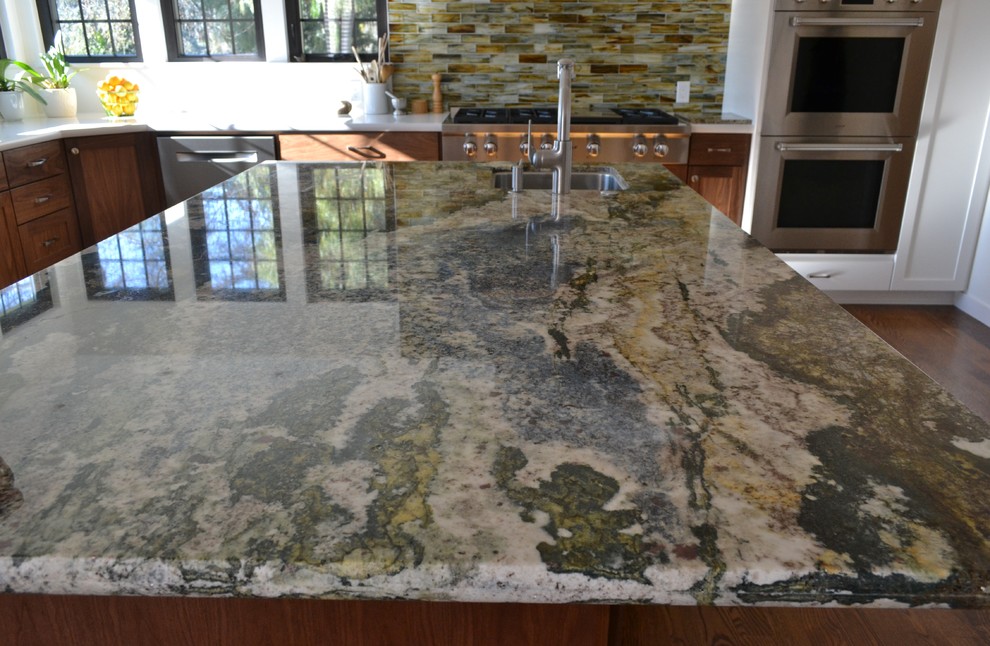 Example of a large transitional l-shaped medium tone wood floor and brown floor kitchen design in San Francisco with shaker cabinets, medium tone wood cabinets, quartz countertops, metallic backsplash, glass tile backsplash, white appliances, an island and white countertops
