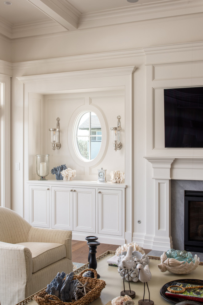 На фото: открытая гостиная комната в классическом стиле с белыми стенами, паркетным полом среднего тона, стандартным камином, фасадом камина из дерева, телевизором на стене, кессонным потолком и панелями на части стены с