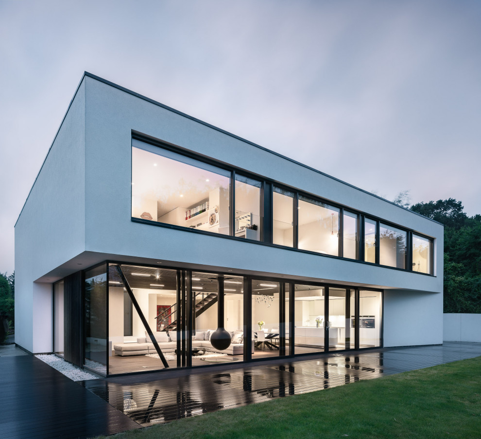 This is an example of a mid-sized contemporary two-storey white house exterior in London with a flat roof.