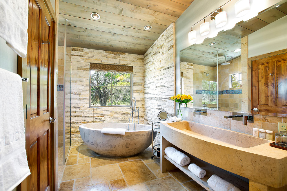 Design ideas for a country master bathroom in Austin with a trough sink, open cabinets, a freestanding tub, a curbless shower, beige tile, stone tile and concrete floors.