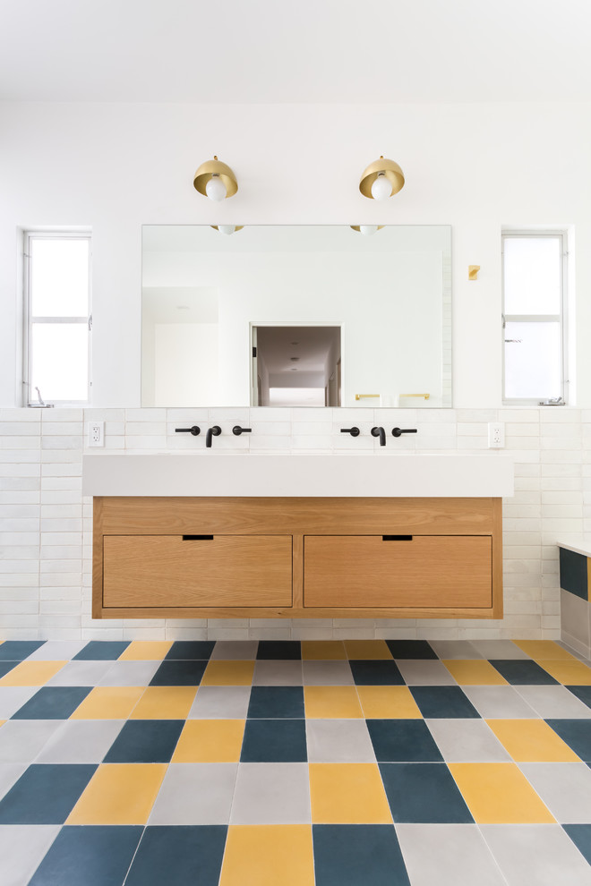 Inspiration for a mid-sized midcentury bathroom in Los Angeles with flat-panel cabinets, light wood cabinets, a drop-in tub, an alcove shower, a one-piece toilet, white tile, ceramic tile, white walls, cement tiles, an undermount sink, engineered quartz benchtops, a hinged shower door and white benchtops.