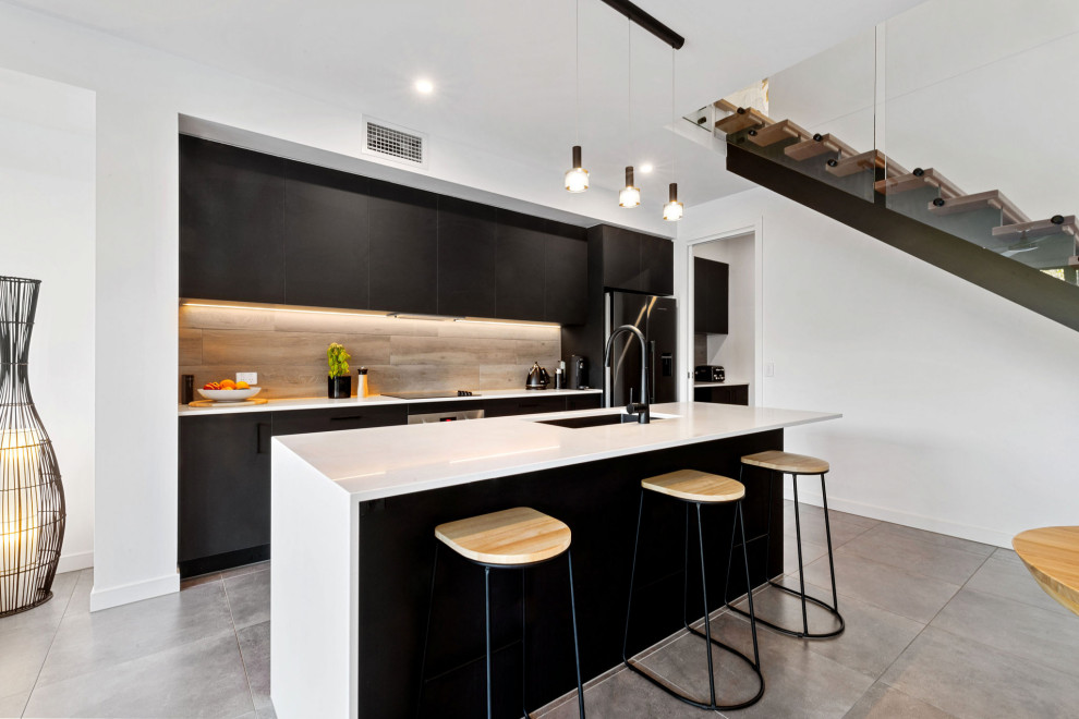 Design ideas for a mid-sized contemporary galley kitchen in Sunshine Coast with an undermount sink, flat-panel cabinets, black cabinets, beige splashback, black appliances, with island, grey floor and white benchtop.
