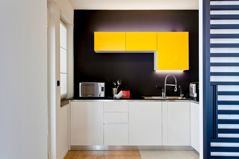 Small contemporary l-shaped separate kitchen in Other with an undermount sink, flat-panel cabinets, yellow cabinets, quartz benchtops, black splashback, no island, medium hardwood floors and brown floor.