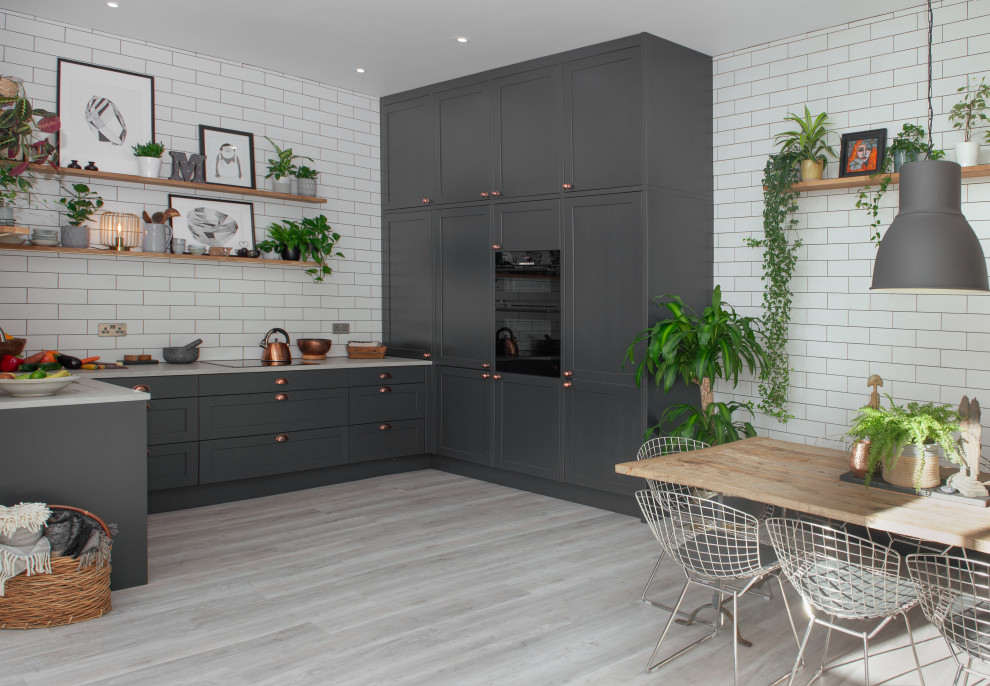 Design ideas for a medium sized traditional u-shaped open plan kitchen in Cornwall with a built-in sink, shaker cabinets, grey cabinets, concrete worktops, white splashback, glass tiled splashback, black appliances, laminate floors, no island and white worktops.