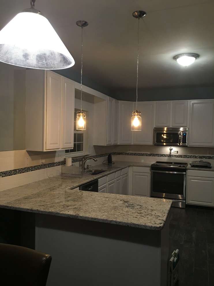 Example of a mid-sized transitional u-shaped ceramic tile eat-in kitchen design with an undermount sink, raised-panel cabinets, white cabinets, granite countertops, subway tile backsplash, stainless steel appliances, a peninsula and white backsplash