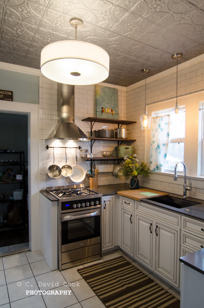 Example of a small transitional u-shaped ceramic tile enclosed kitchen design with an undermount sink, raised-panel cabinets, white cabinets, solid surface countertops, white backsplash, subway tile backsplash, stainless steel appliances and no island