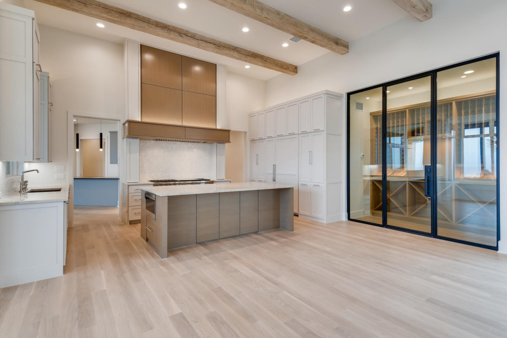 Design ideas for a mid-sized modern u-shaped eat-in kitchen in Denver with a drop-in sink, shaker cabinets, white cabinets, quartzite benchtops, white splashback, marble splashback, panelled appliances, light hardwood floors, with island and white benchtop.