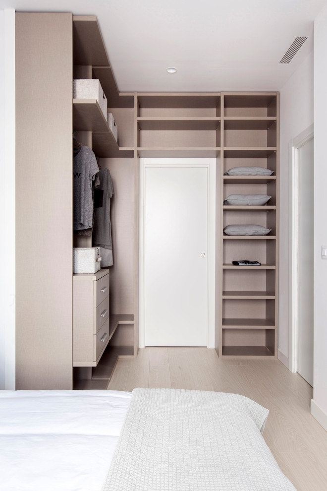 Inspiration for a small contemporary gender-neutral walk-in wardrobe in Madrid with open cabinets, light hardwood floors, beige floor and beige cabinets.