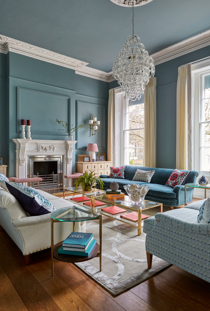 Стильный дизайн: гостиная комната в классическом стиле с синими стенами, паркетным полом среднего тона, стандартным камином, коричневым полом и панелями на части стены - последний тренд