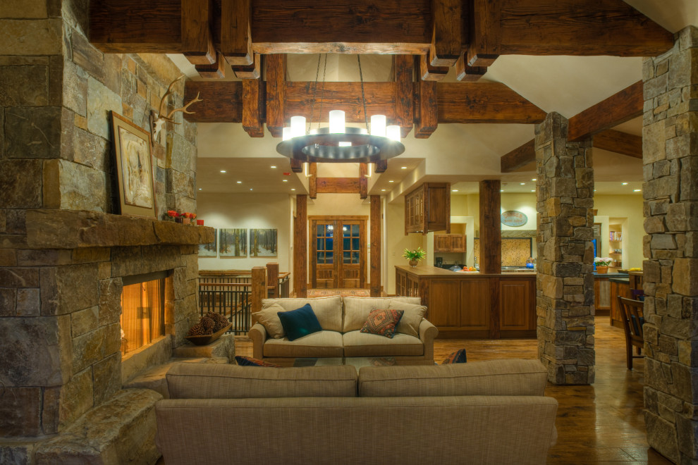 This is an example of a country family room in Other with a stone fireplace surround and exposed beam.