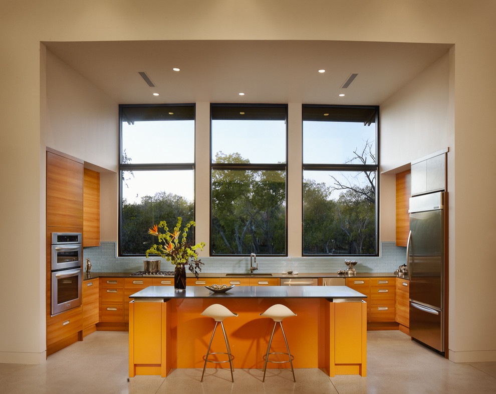 This is an example of a modern u-shaped kitchen in New York with flat-panel cabinets, medium wood cabinets, blue splashback, stainless steel appliances, an integrated sink and with island.
