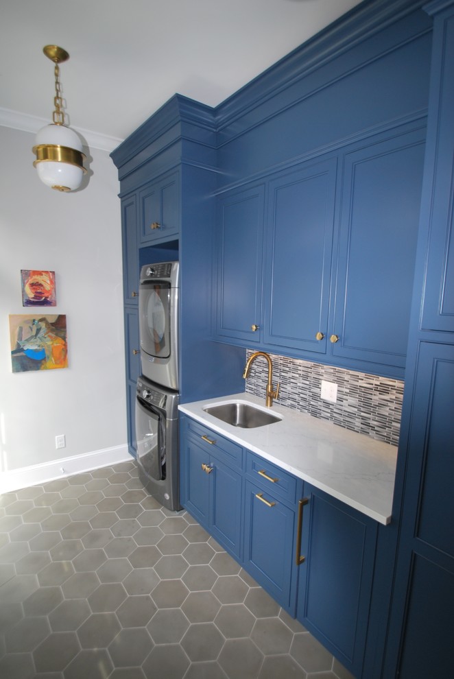 Inspiration for a mid-sized transitional single-wall utility room in DC Metro with an undermount sink, beaded inset cabinets, blue cabinets, quartz benchtops, grey walls, concrete floors, a stacked washer and dryer, grey floor and white benchtop.