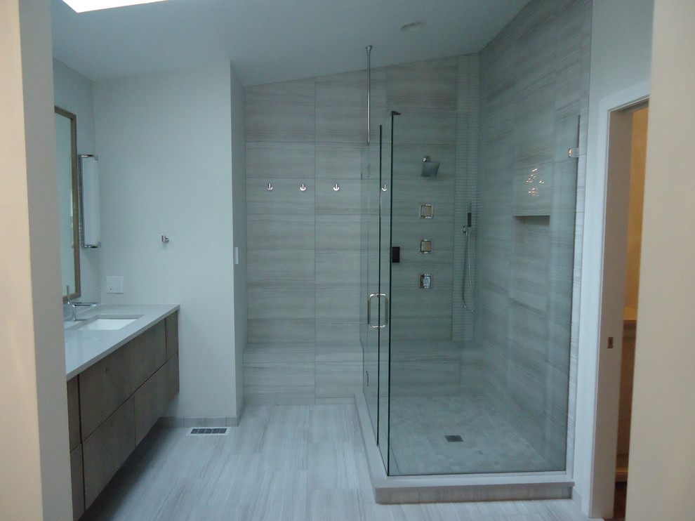 Photo of a mid-sized contemporary master bathroom in Other with flat-panel cabinets, brown cabinets, a freestanding tub, an open shower, a two-piece toilet, gray tile, glass tile, grey walls, ceramic floors, an undermount sink and engineered quartz benchtops.