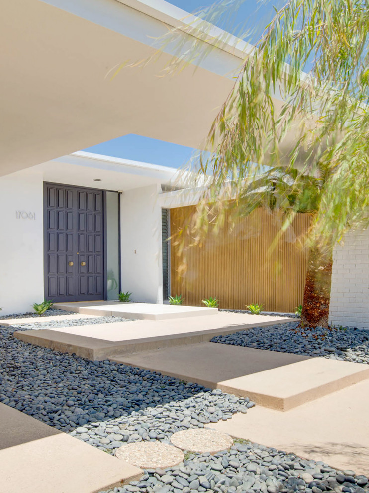 This is an example of a mid-sized midcentury one-storey white house exterior in Phoenix with painted brick siding, a flat roof and a white roof.