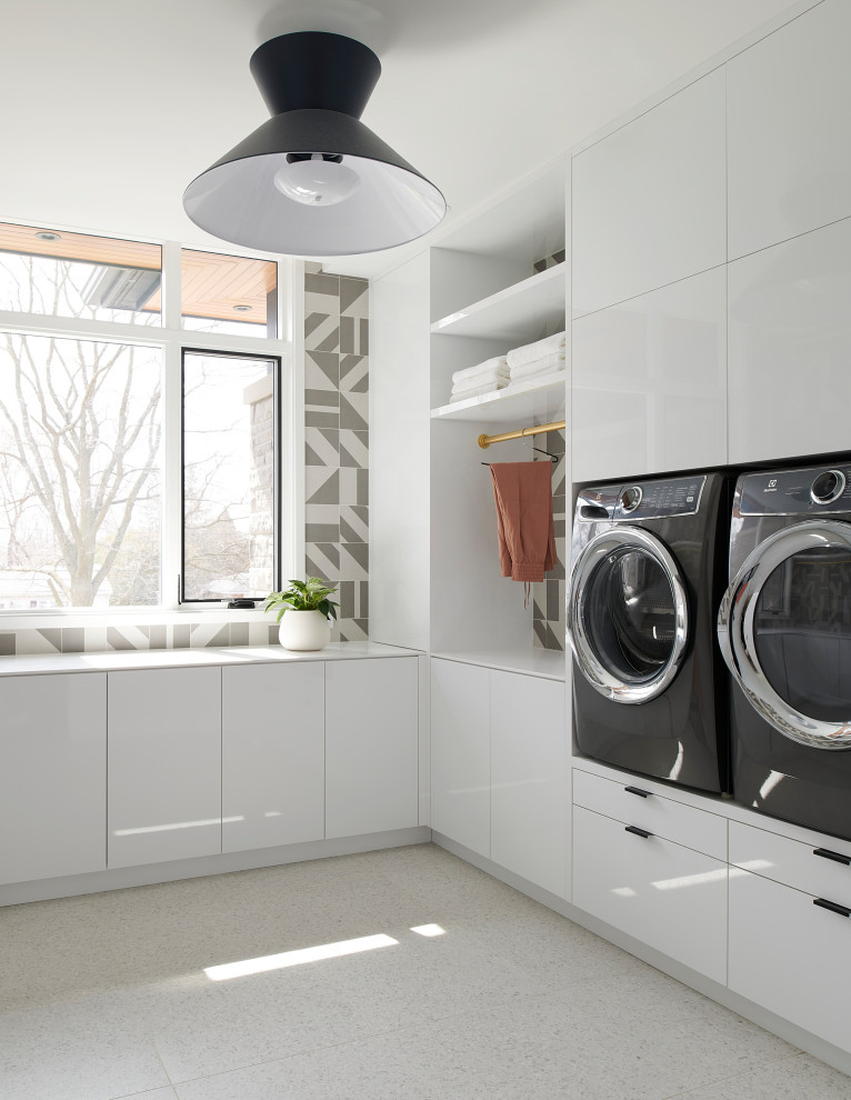Photo of a large contemporary u-shaped dedicated laundry room in Toronto with an undermount sink, flat-panel cabinets, white cabinets, solid surface benchtops, grey splashback, porcelain splashback, white walls, porcelain floors, a side-by-side washer and dryer, white floor and white benchtop.