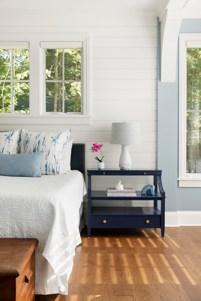 Imagen de dormitorio principal costero grande con paredes azules, suelo de madera en tonos medios y suelo marrón