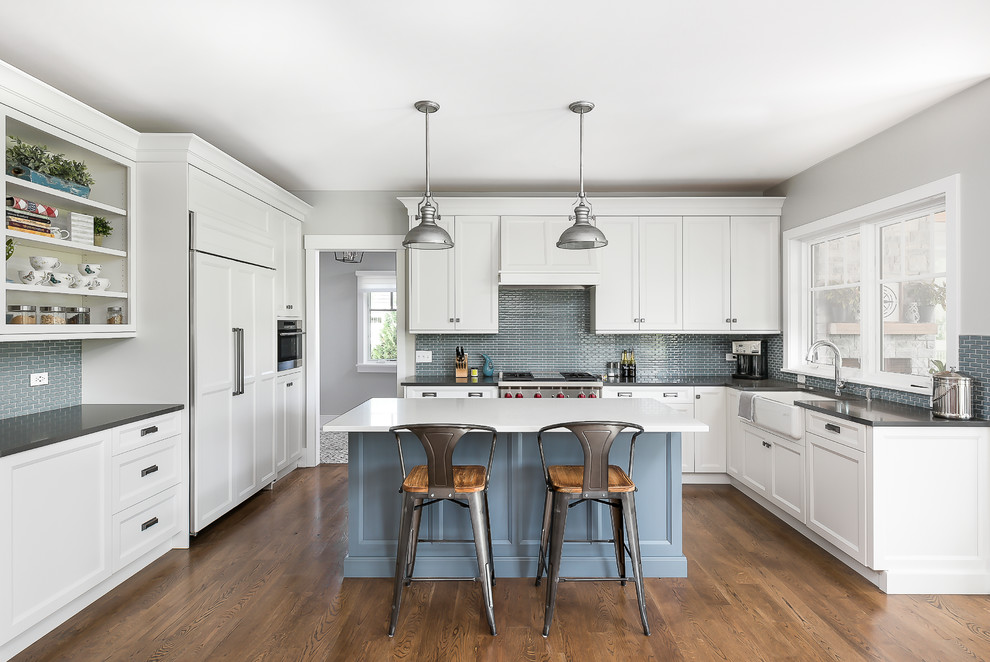 Design ideas for a mid-sized transitional u-shaped open plan kitchen in Chicago with a farmhouse sink, beaded inset cabinets, white cabinets, quartz benchtops, blue splashback, porcelain splashback, panelled appliances, with island, brown floor, white benchtop and dark hardwood floors.