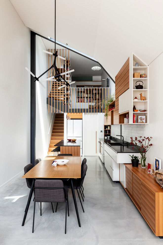 This is an example of a mid-sized contemporary dining room in Sydney with concrete floors, grey floor and white walls.