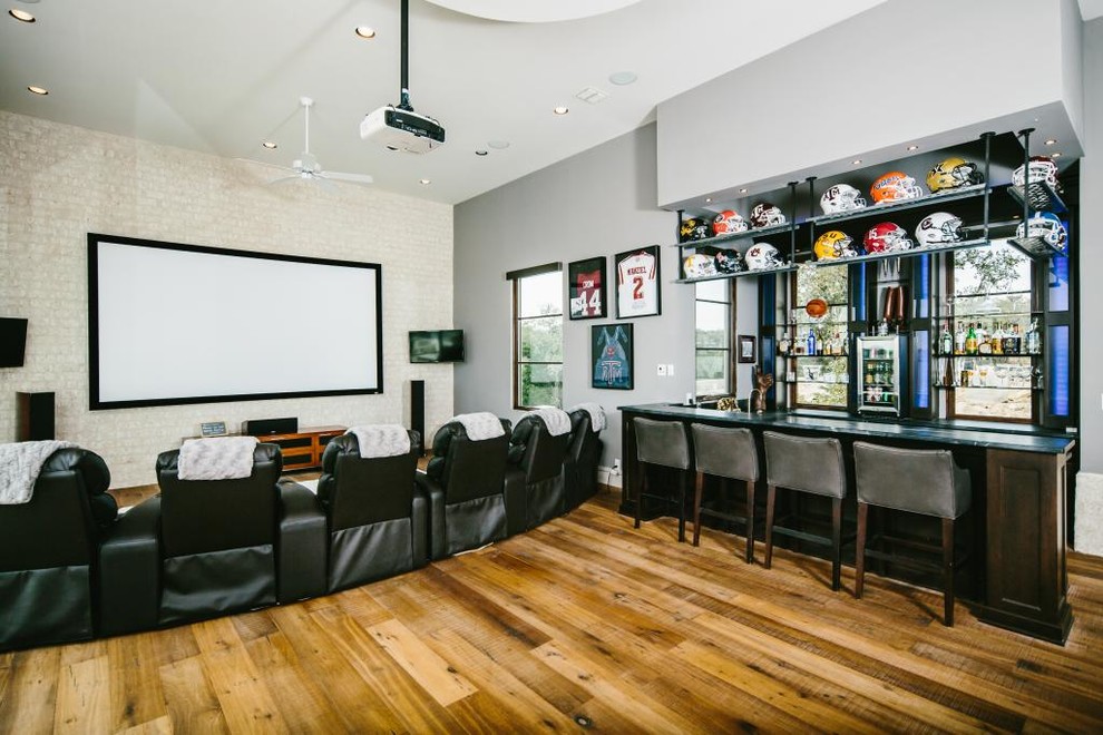 This is an example of a traditional home theatre in Austin with white walls, medium hardwood floors and a projector screen.