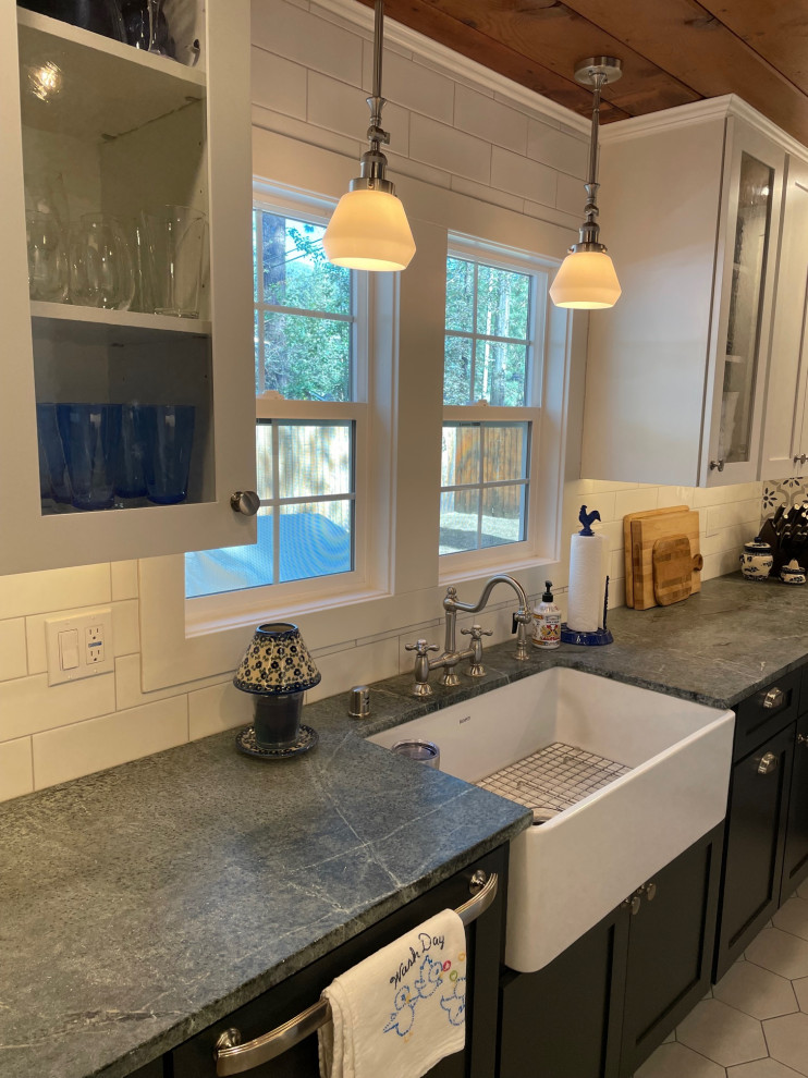 This is an example of a small country kitchen in Other with a belfast sink, shaker cabinets, blue cabinets, soapstone worktops, white splashback, metro tiled splashback, white appliances, porcelain flooring, grey floors and a wood ceiling.
