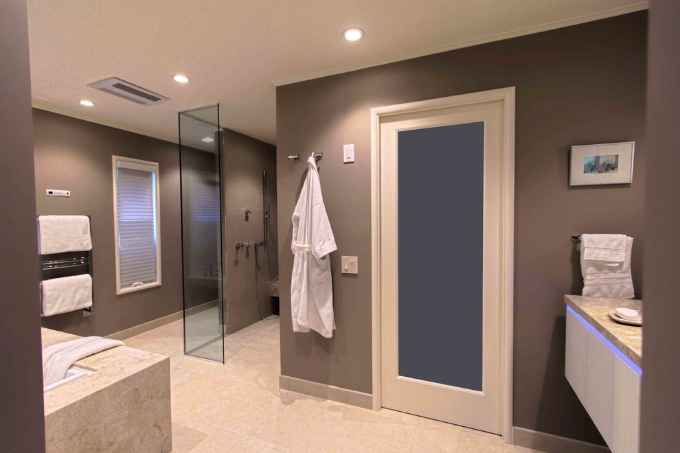 Large contemporary master bathroom in San Francisco with a curbless shower, a one-piece toilet, brown walls, porcelain floors, flat-panel cabinets, beige cabinets, limestone benchtops, beige tile, porcelain tile and an undermount tub.