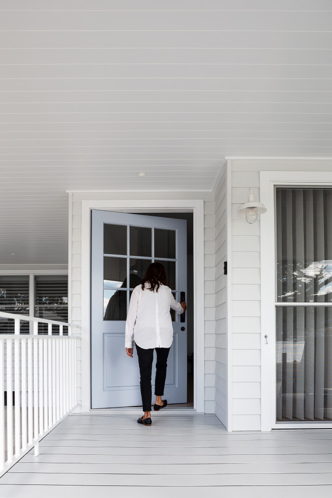 Mittelgroße Maritime Haustür mit weißer Wandfarbe, Betonboden, Drehtür, blauer Haustür, grauem Boden und Holzdielenwänden in Sydney