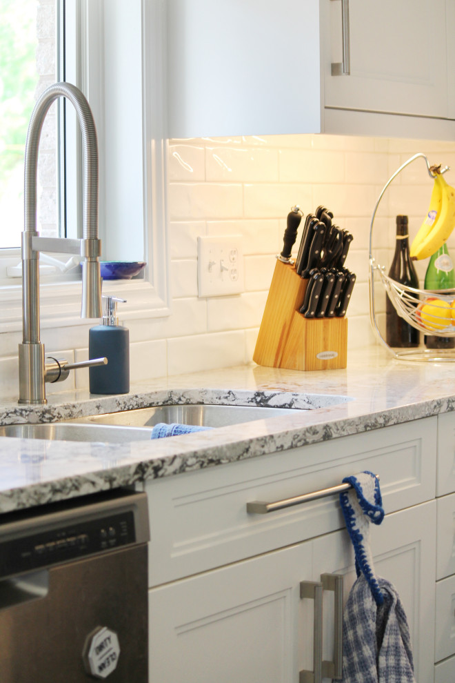 Eat-in kitchen - large transitional u-shaped eat-in kitchen idea with shaker cabinets, white cabinets, quartz countertops, white backsplash, subway tile backsplash, stainless steel appliances, an island and gray countertops