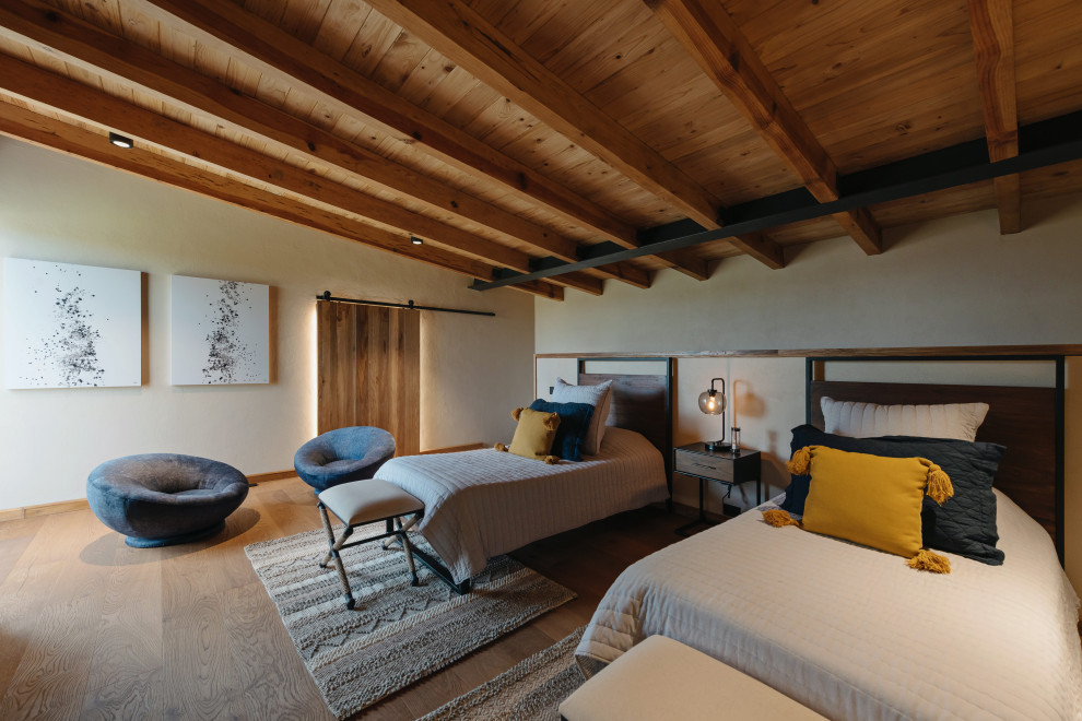 На фото: большая гостевая спальня (комната для гостей) в стиле кантри с бежевыми стенами, темным паркетным полом, коричневым полом и деревянным потолком с