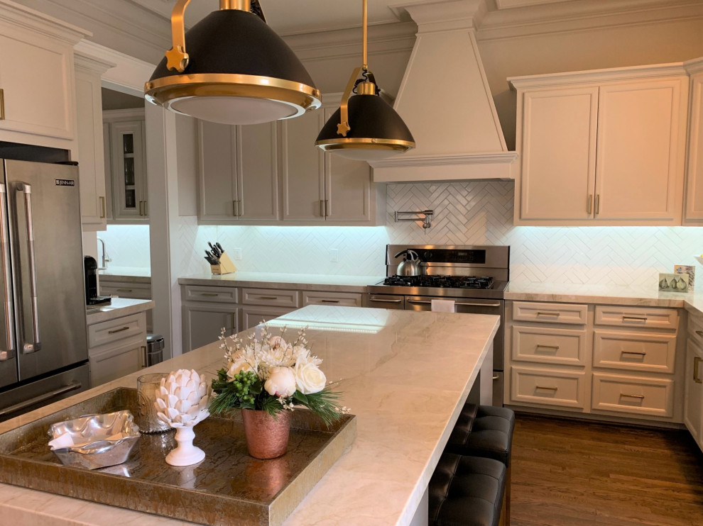 Mid-sized arts and crafts u-shaped open plan kitchen in Houston with an undermount sink, shaker cabinets, white cabinets, quartzite benchtops, white splashback, subway tile splashback, stainless steel appliances, medium hardwood floors, with island, brown floor and white benchtop.