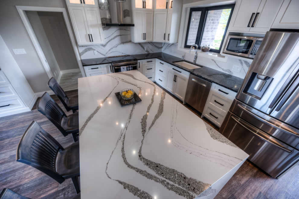 Example of a transitional eat-in kitchen design with shaker cabinets, white cabinets, stainless steel appliances and an island