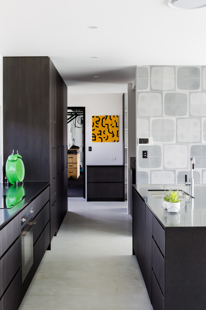 Mid-sized galley open plan kitchen in Gold Coast - Tweed with a double-bowl sink, black cabinets, quartz benchtops, black appliances, concrete floors, with island, grey floor and black benchtop.