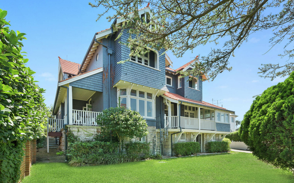 This is an example of a large traditional three-storey brick blue house exterior in Sydney with a gable roof and a tile roof.