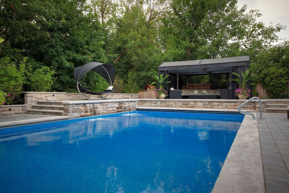 Photo of a large contemporary backyard rectangular lap pool in Toronto with concrete pavers.