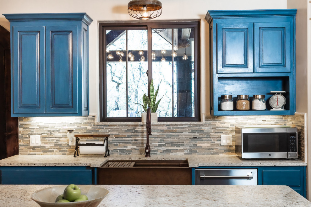 Mittelgroße Landhaus Wohnküche in L-Form mit Landhausspüle, profilierten Schrankfronten, blauen Schränken, Küchenrückwand in Beige, Küchengeräten aus Edelstahl, dunklem Holzboden, Kücheninsel, braunem Boden und beiger Arbeitsplatte in Dallas