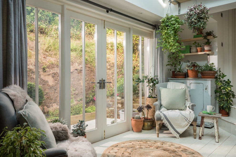 This is an example of a shabby-chic style conservatory in Cornwall with painted wood flooring, a skylight and white floors.