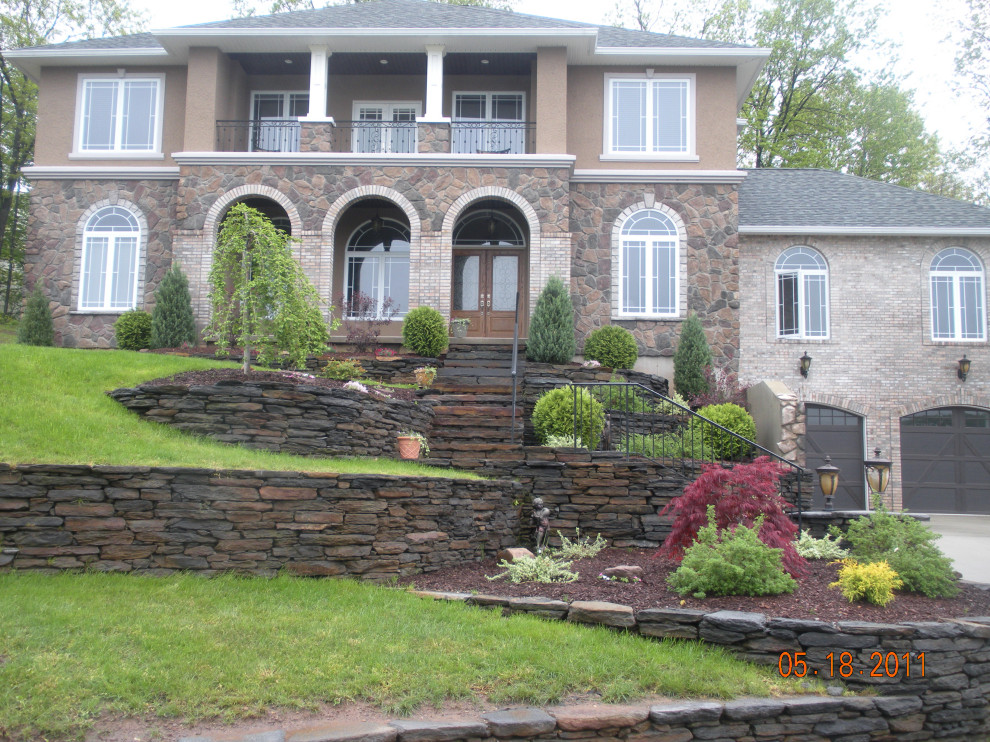 Photo of an expansive mediterranean three-storey house exterior in Boston with stone veneer, a shingle roof and a brown roof.