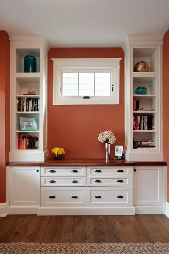 Small arts and crafts home office in Chicago with orange walls, dark hardwood floors and a freestanding desk.