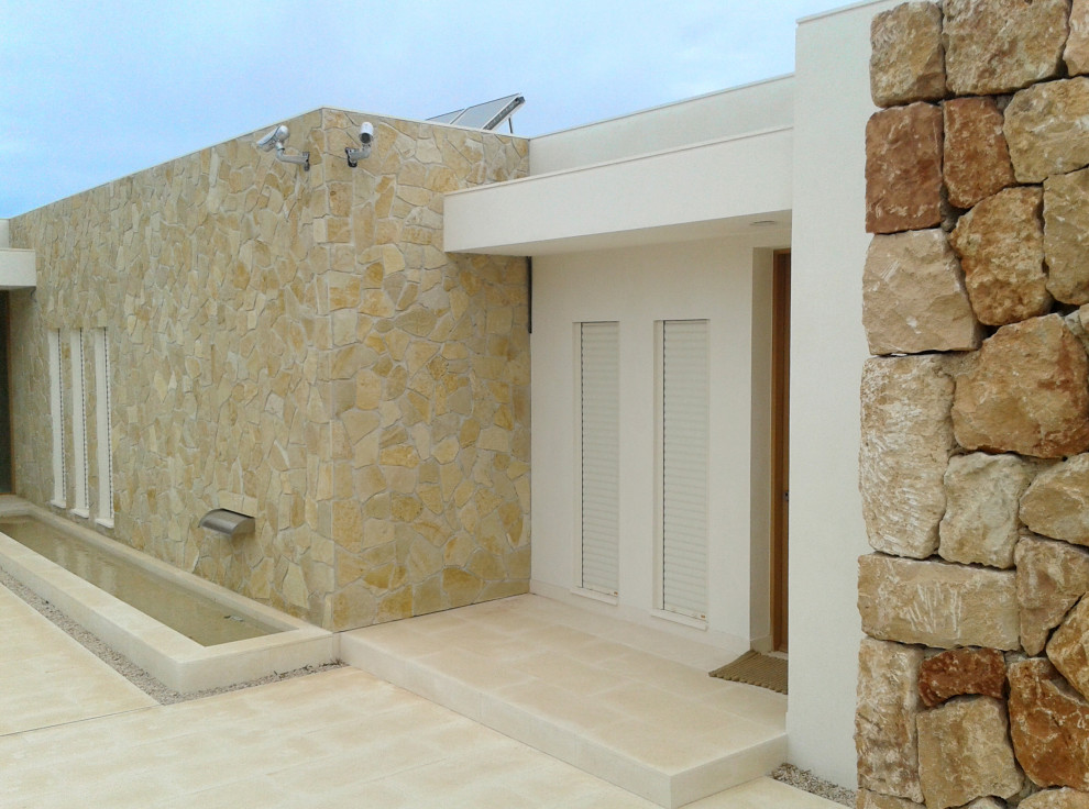 Diseño de puerta principal mediterránea con paredes blancas, puerta de madera en tonos medios y suelo beige