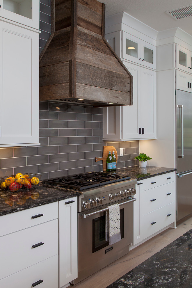 Large transitional u-shaped light wood floor open concept kitchen photo in Orlando with a farmhouse sink, shaker cabinets, white cabinets, quartzite countertops, gray backsplash, ceramic backsplash, stainless steel appliances and an island