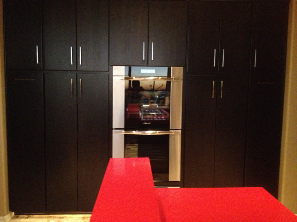This is an example of a large contemporary u-shaped open plan kitchen in Phoenix with an undermount sink, flat-panel cabinets, dark wood cabinets, quartz benchtops, multi-coloured splashback, glass sheet splashback, stainless steel appliances, travertine floors, with island, beige floor and red benchtop.