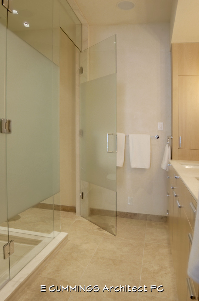 Photo of a mid-sized contemporary master bathroom in Denver with an undermount sink, flat-panel cabinets, light wood cabinets, engineered quartz benchtops, a corner shower, a one-piece toilet, beige tile, stone tile, white walls and limestone floors.