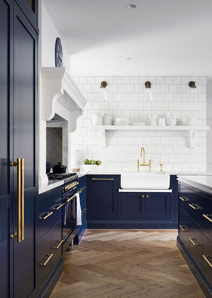 Inspiration for a traditional l-shaped kitchen in Melbourne with a farmhouse sink, shaker cabinets, blue cabinets, white splashback, coloured appliances, medium hardwood floors, with island, brown floor and white benchtop.