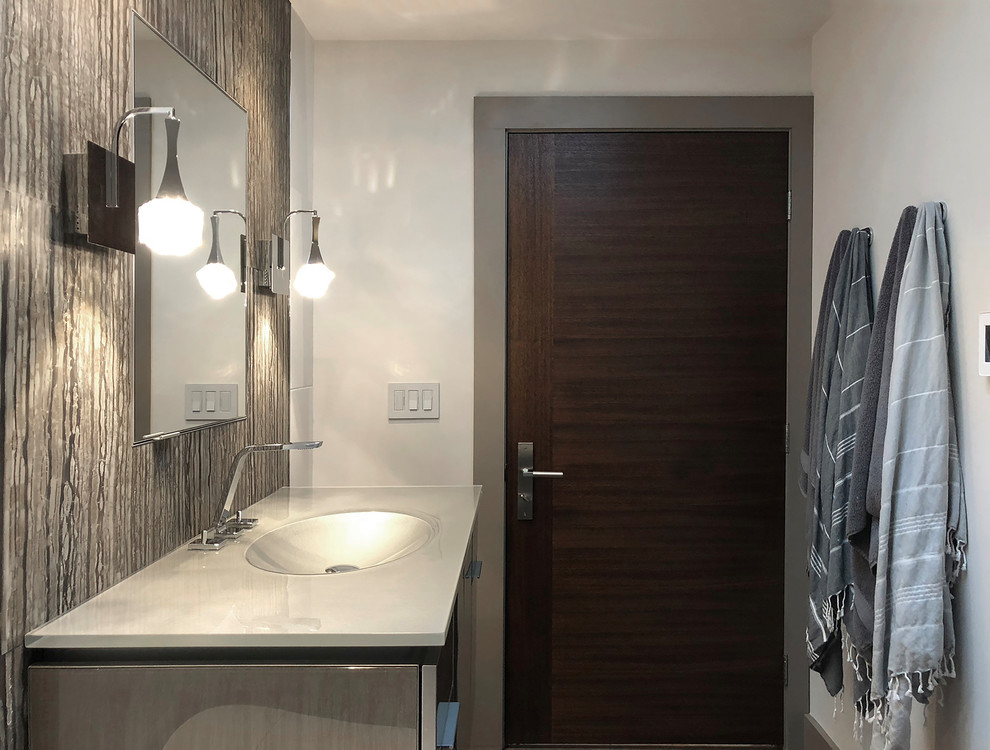 This is an example of a mid-sized modern 3/4 bathroom in Seattle with glass-front cabinets, grey cabinets, a curbless shower, a wall-mount toilet, black and white tile, stone tile, white walls, porcelain floors, an integrated sink, glass benchtops, grey floor, a hinged shower door and grey benchtops.
