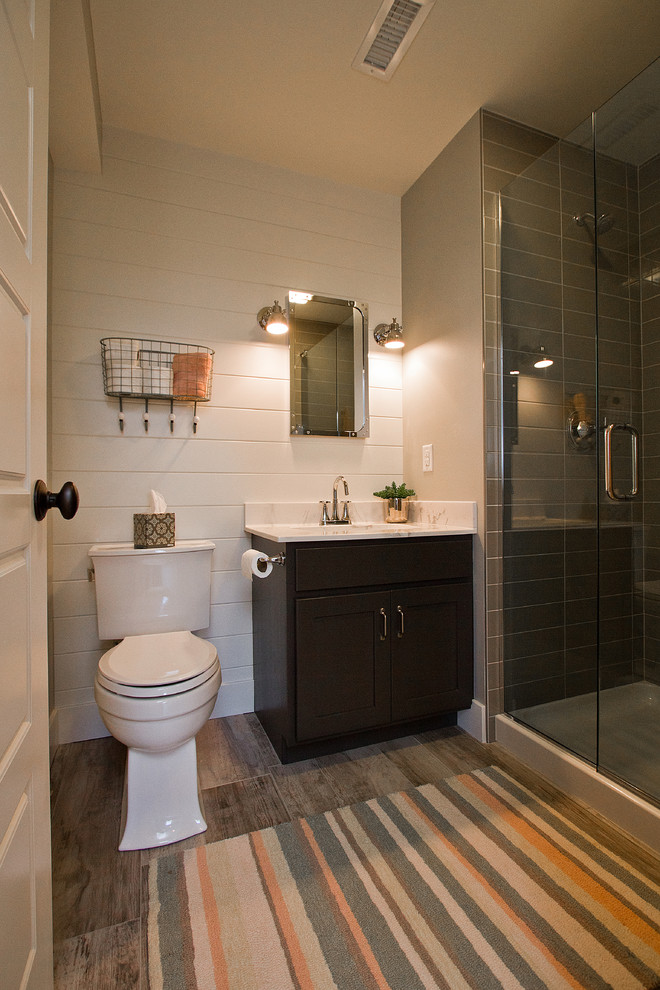 Small arts and crafts 3/4 bathroom in Other with recessed-panel cabinets, black cabinets, a corner shower, a two-piece toilet, white walls, vinyl floors, a drop-in sink, marble benchtops, brown floor and a hinged shower door.
